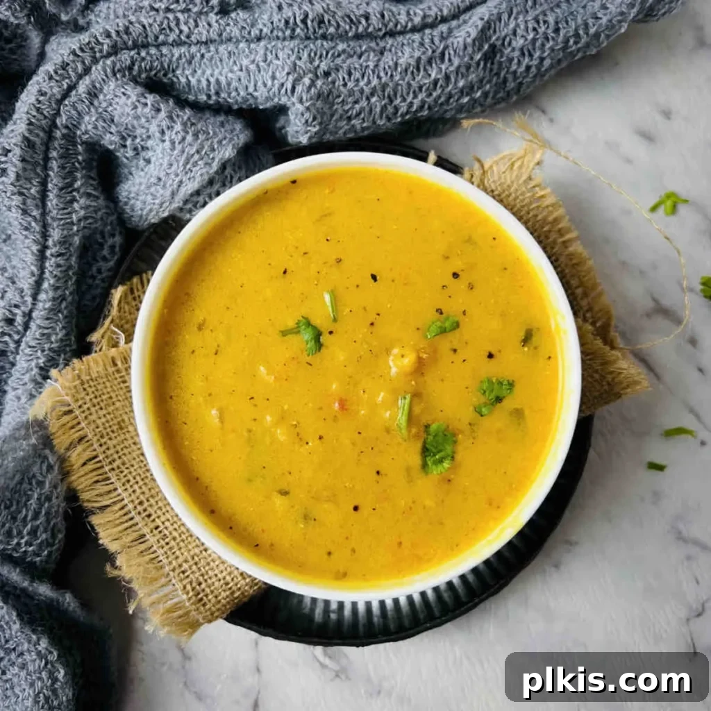 Over 30 Quick and Flavorful Vegan Instant Pot Recipes 14 completed Mulligatawny Soup in a white bowl against a gray surface with a blue towel in the background