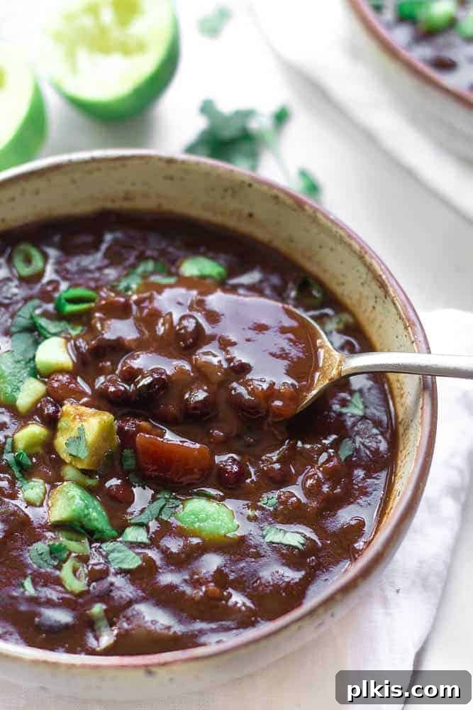 Over 30 Quick and Flavorful Vegan Instant Pot Recipes 15 completed black bean soup in a light gray bowl against a white surface with ingredients scattered in the background