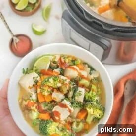 Barley vegetable soup in a white bowl next to a full Instant Pot.