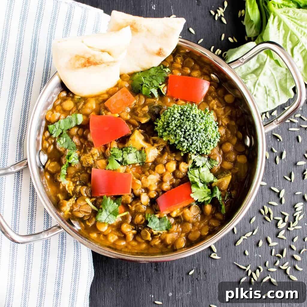 Over 30 Quick and Flavorful Vegan Instant Pot Recipes 21 completed masala lentil curry in a pot against a gray background with bread in the pot