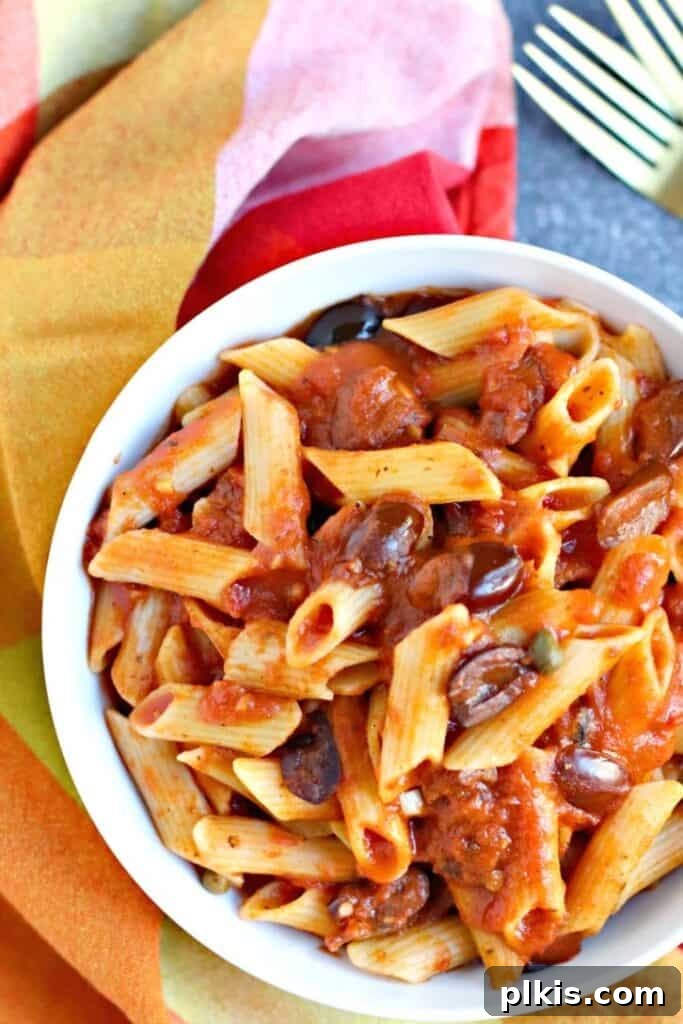 Over 30 Quick and Flavorful Vegan Instant Pot Recipes 24 completed Pasta Puttansca in a white bowl against a brown surface with a red and pink towel in the background