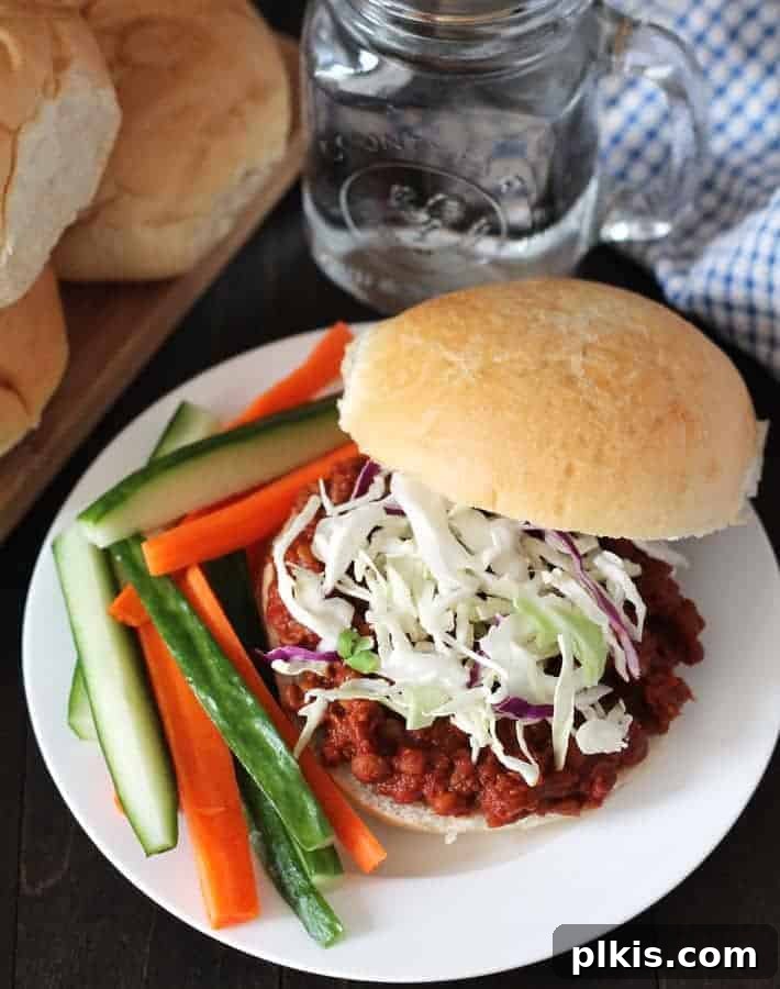 Over 30 Quick and Flavorful Vegan Instant Pot Recipes 26 completed lentil sloppy joe plated on a white plate with veggies on the side against a brown surface