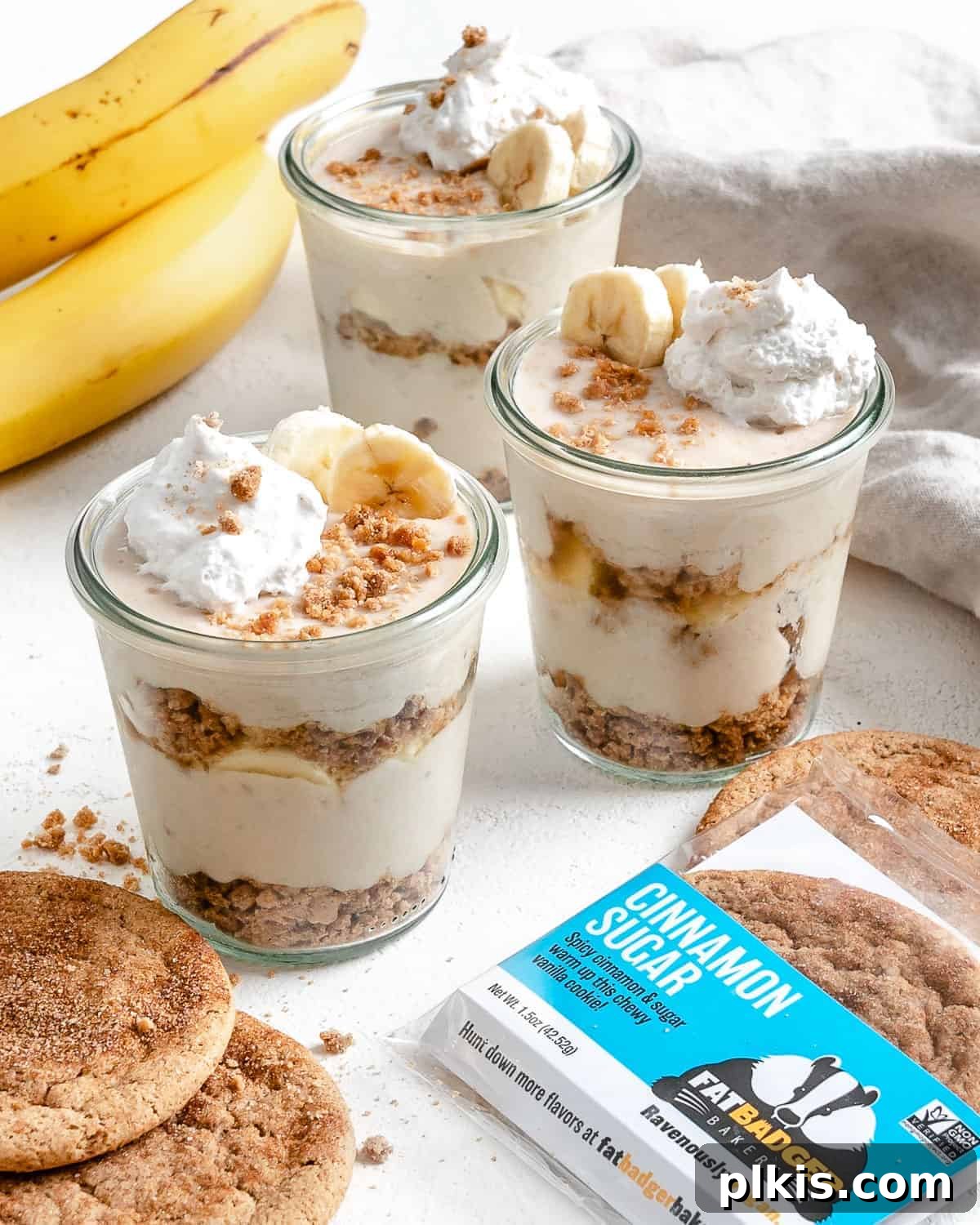 Layered Banana Dream 11 Several completed vegan banana parfaits in glass jars with a cookie in the forefront, ready to be enjoyed