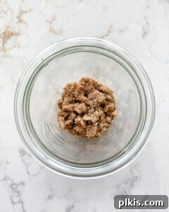 Cup of nuts in a clear container against a white marble surface, indicating optional add-ins