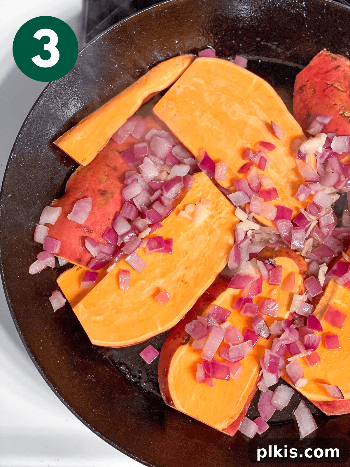 Signature Sweet Potato Sandwich 6 Process shot showing sweet potato slices cooking with onions and garlic in a skillet.