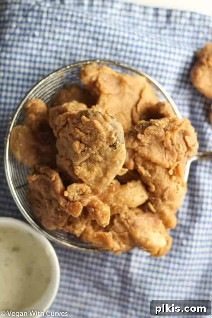 50 Quick Vegan Bites 73 Completed fried oyster mushrooms beautifully plated on a white dish against a blue and white cloth background.