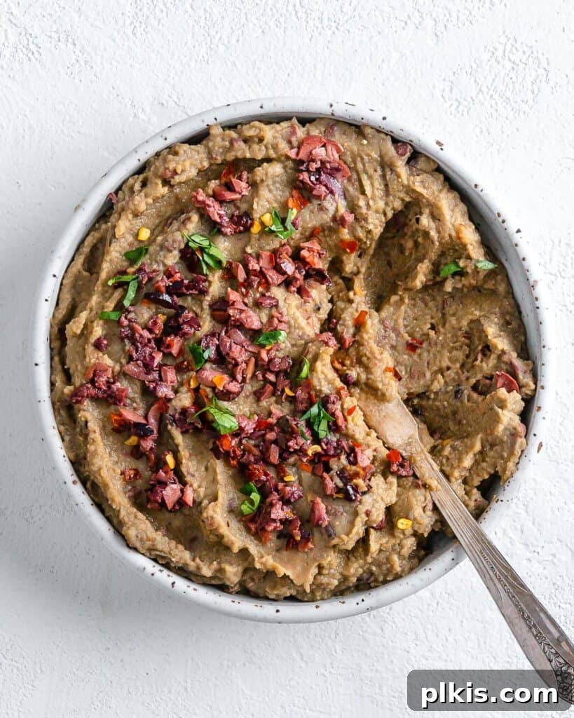50 Quick Vegan Bites 14 A completed Spicy Lentil Kalamata Dip served in a white bowl against a pristine white background.