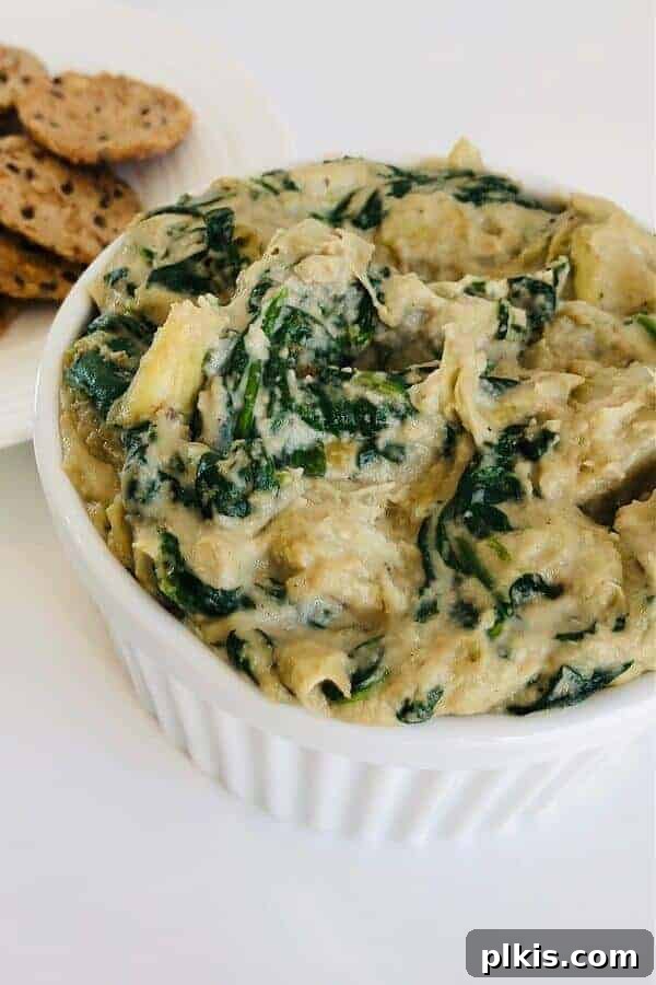 50 Quick Vegan Bites 16 A completed spinach artichoke dip served in a small white bowl against a white background.