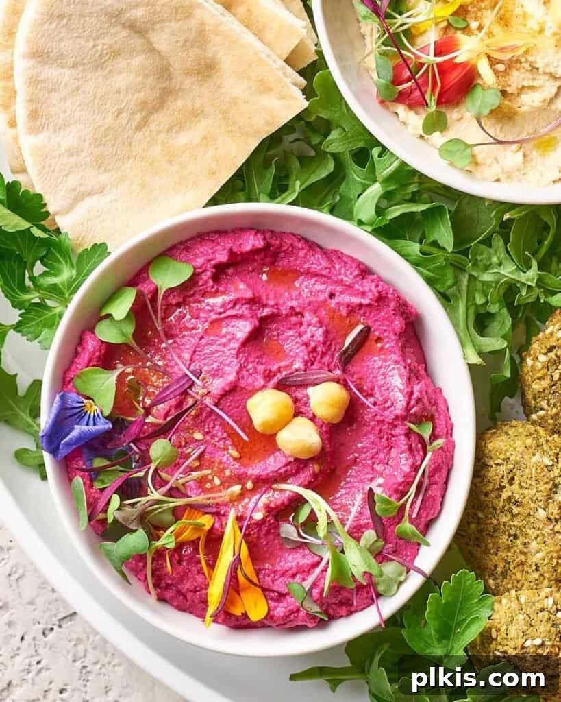 50 Quick Vegan Bites 19 A completed Pink Beetroot Hummus in a white bowl, artfully surrounded by fresh greens and bread slices.