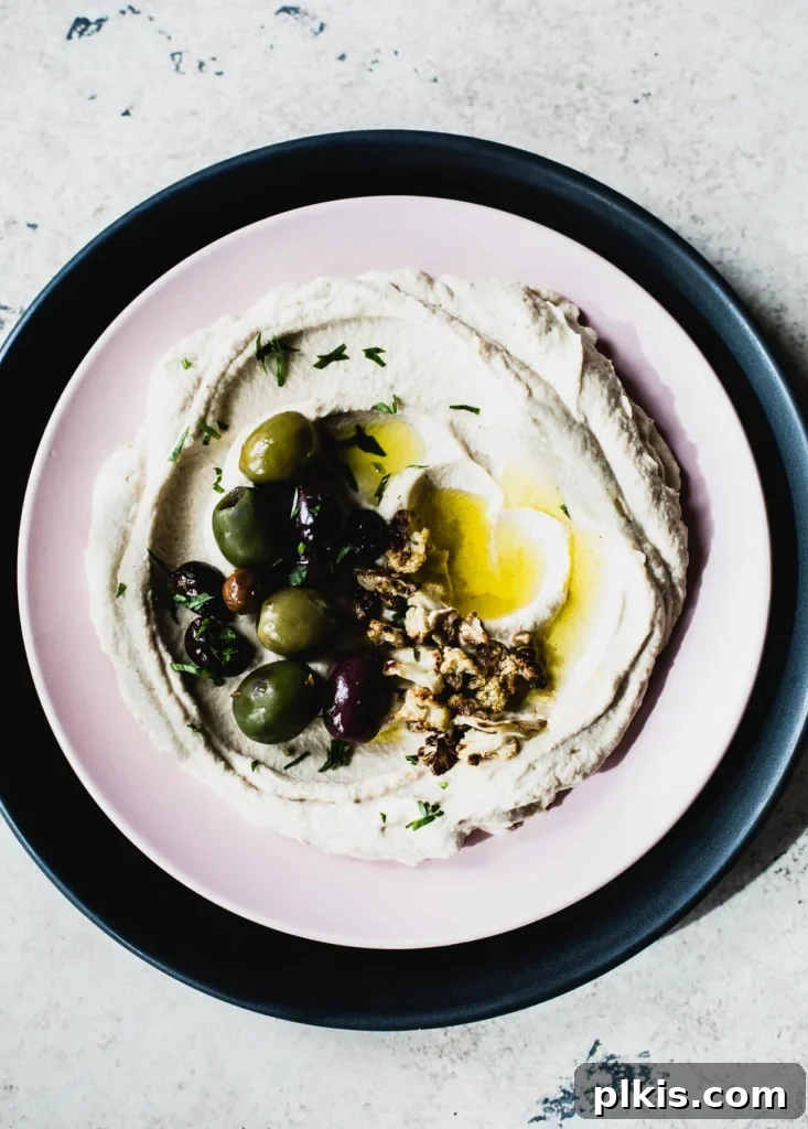 50 Quick Vegan Bites 20 A completed Roasted Cauliflower Dip presented in a stylish black bowl against a clean white background.