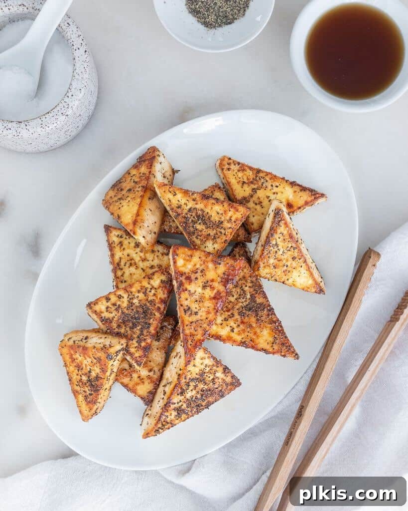 50 Quick Vegan Bites 25 Completed Sweet and Salty Tofu triangles artfully arranged on a white platter against a crisp white background.