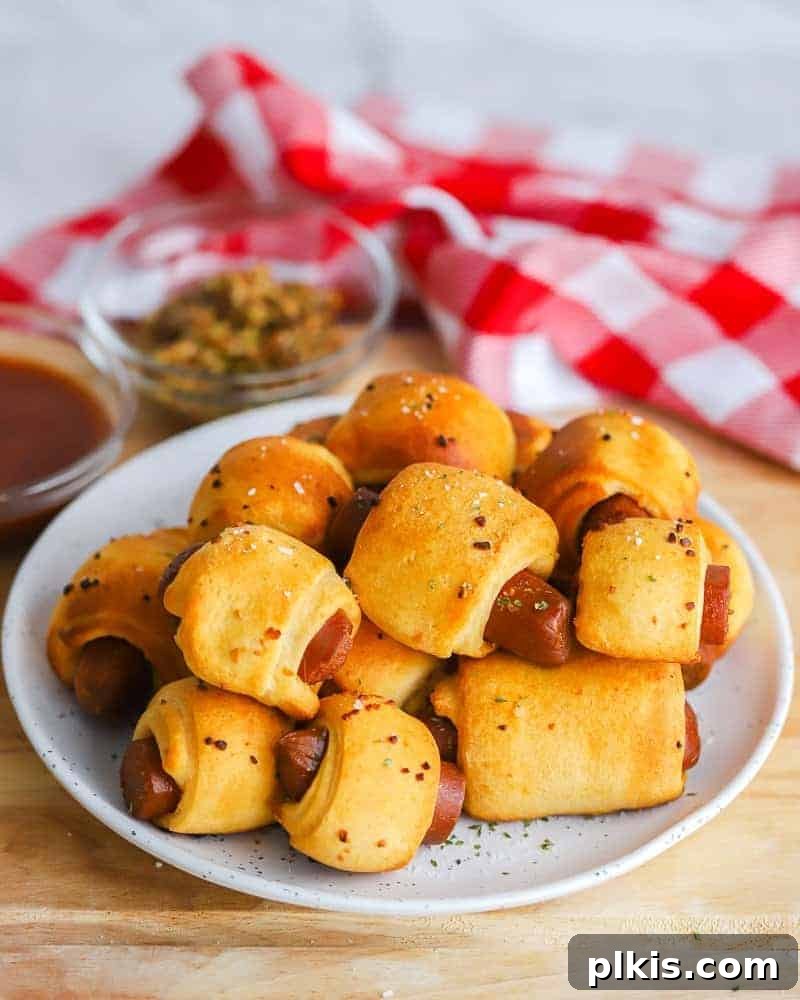 50 Quick Vegan Bites 33 Several completed Vegan Pigs in a Blanket arranged on a white plate with a red and white towel in the background.