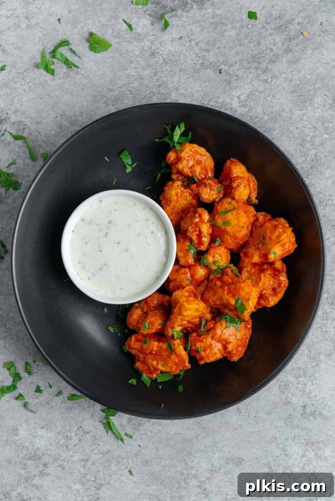 50 Quick Vegan Bites 35 Completed Air Fryer Buffalo Cauliflower Wings elegantly plated on a black dish against a stylish gray background.