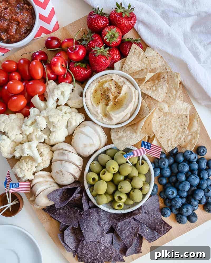 50 Quick Vegan Bites 7 A completed charcuterie board bursting with an assortment of red, white, and blue foods against a white surface, ideal for Fourth of July.