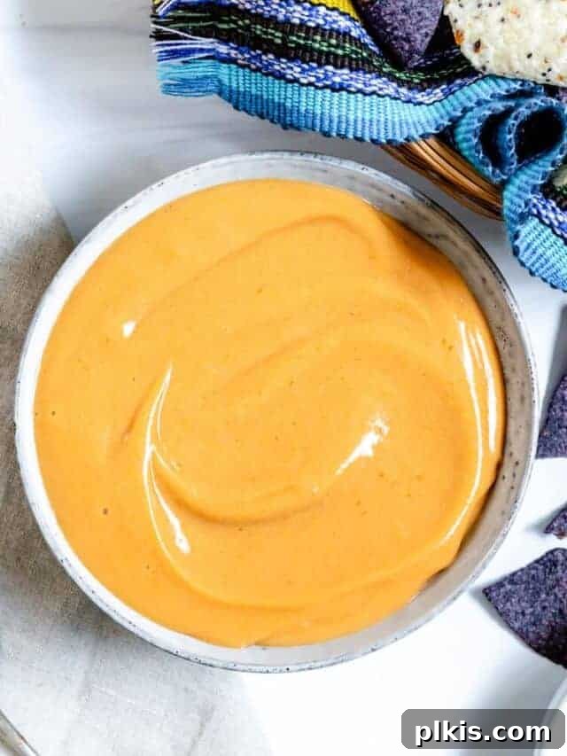 50 Quick Vegan Bites 41 Top view of a white bowl filled with luscious vegan nacho cheese sauce.