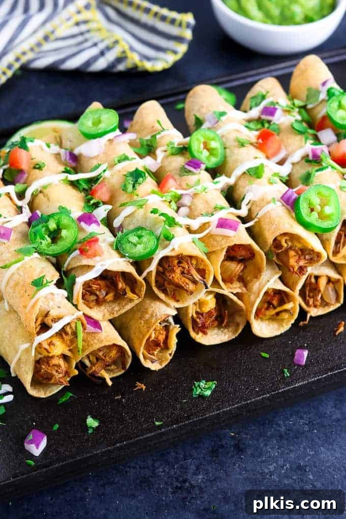 50 Quick Vegan Bites 43 Completed Vegan Baked Taquitos arranged on a black surface, elegantly dressed with fresh veggies and a drizzle of sauce.