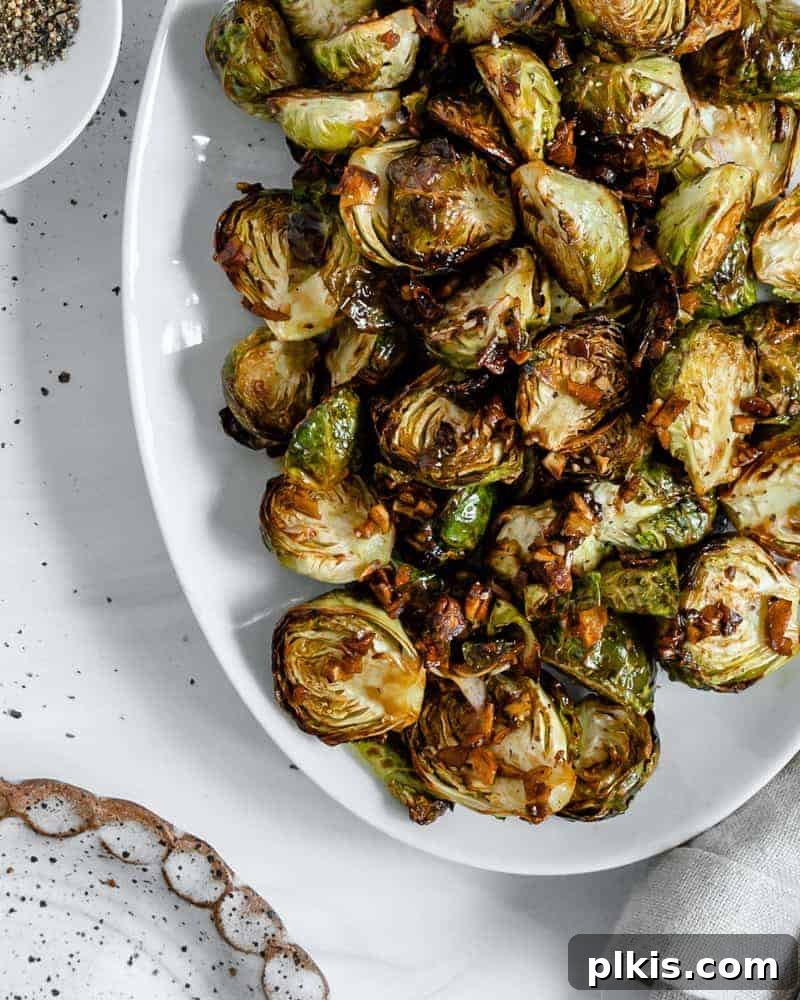 50 Quick Vegan Bites 52 Finished Crispy Air Fryer Brussels Sprouts plated beautifully on a white dish against a clean white background.