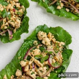 three completed larb salad servings against a white surface
