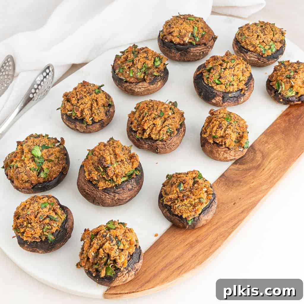 50 Quick Vegan Bites 68 Several stuffed mushrooms artfully arranged on a white serving platter, ready to be enjoyed.