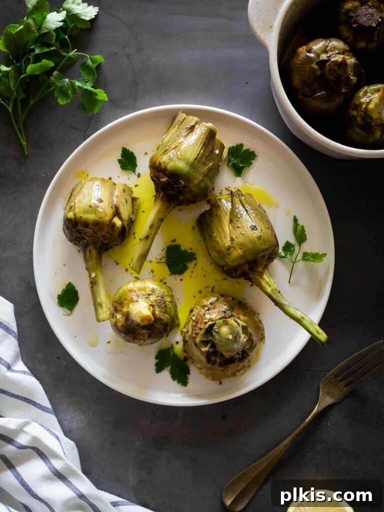 50 Quick Vegan Bites 72 Completed Roman-Style Artichokes beautifully plated on a white dish against a dark background.