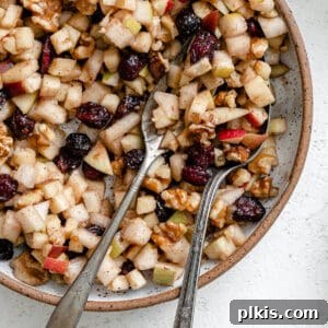 close up on two spoons in a bowl of chunky charoset.