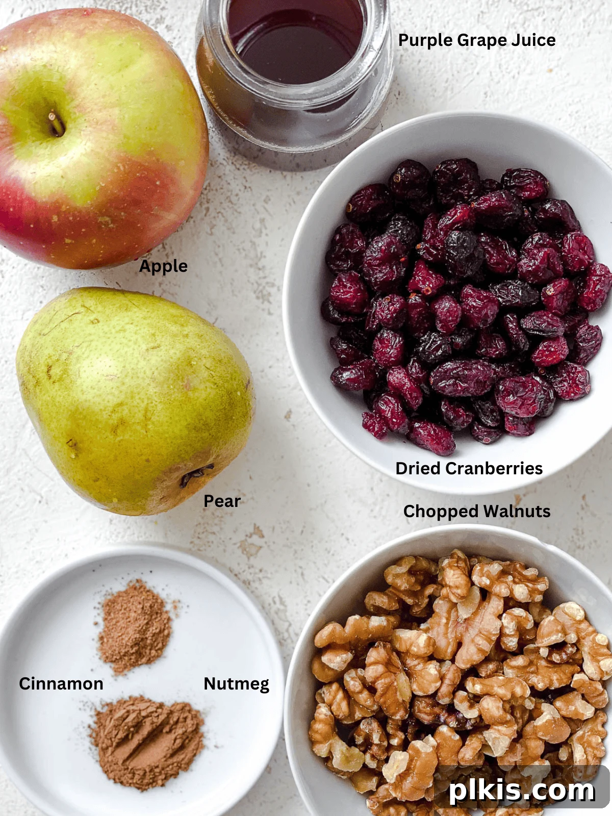Rustic Charoset Delight 3 ingredients for Chunky Charoset laid out on a white surface, including apples, pears, walnuts, grape juice, and spices.