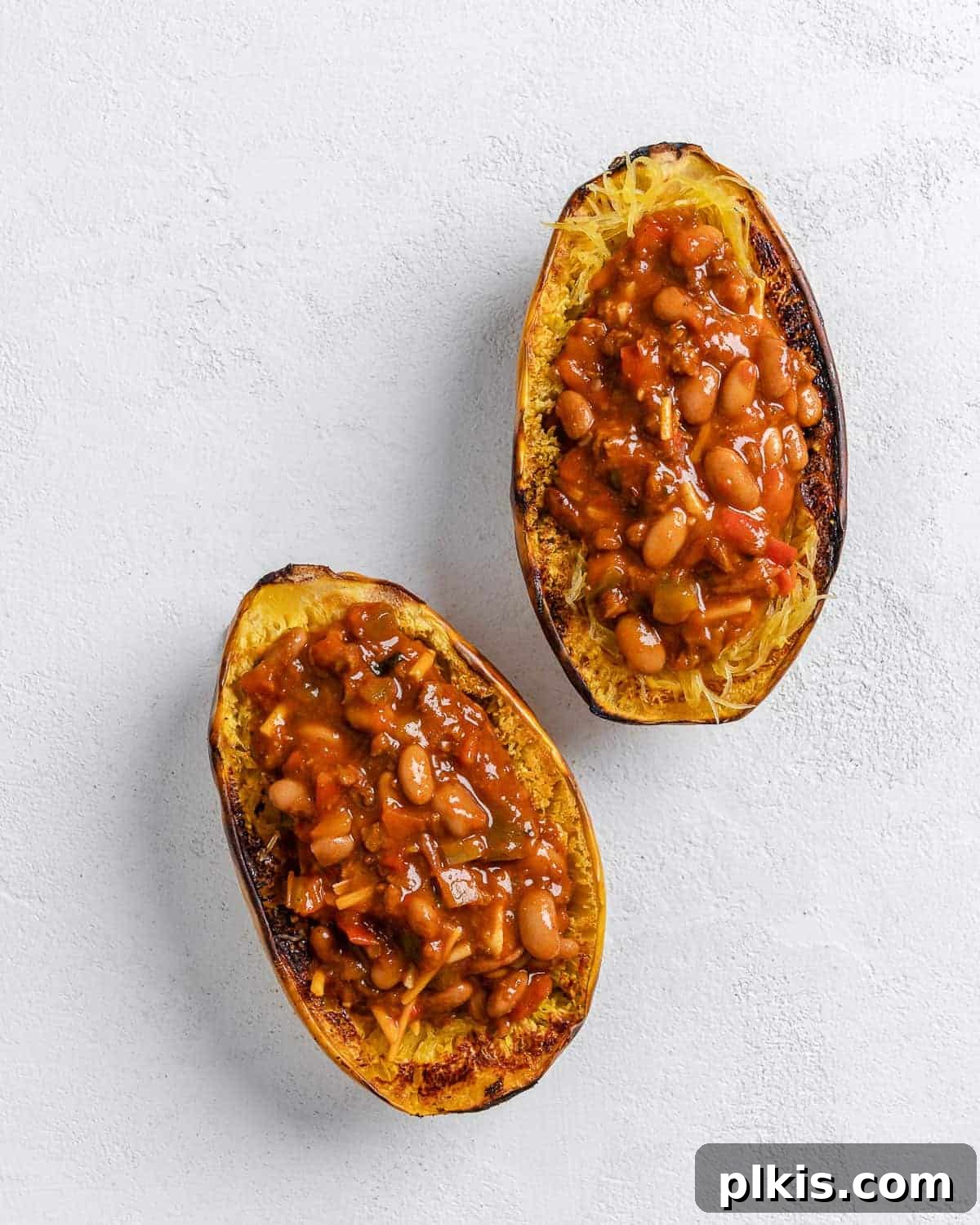 Golden Spaghetti Squash Bowls with Spicy Chili Cheese 9 A completed stuffed spaghetti squash with chili, ready to serve, against a white background.