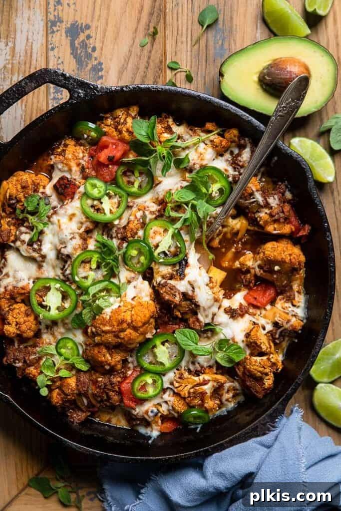 Quick & Delicious: 30-Minute Vegan Dinners 40 Completed Vegan Cheesy Cauliflower Casserole in a black skilled against a brown background.