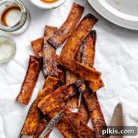 A pile of savory, sauce-covered and baked vegan tofu bacon strips.