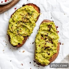 A slice of vegan avocado toast, artfully prepared on a white surface.