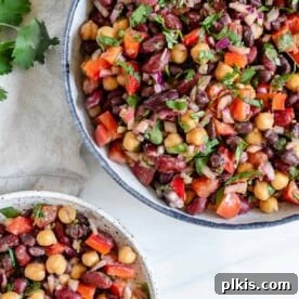 A mixed bean salad in a serving bowl, with an individual portion on the side.