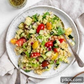 A white plate with Vegan Greek Millet Salad, featuring Mediterranean ingredients.