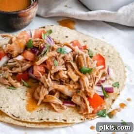 Jackfruit carnitas served on tortillas, with additional ingredients in the background.