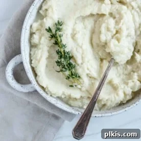 Creamy mashed cauliflower in a white dish with a spoon.