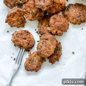 Golden-brown Quinoa Tater Tots on a white surface, with a fork and sauce nearby.