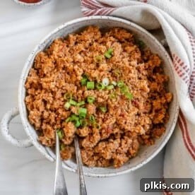 Spanish Cauliflower Rice in a white bowl with two utensils.