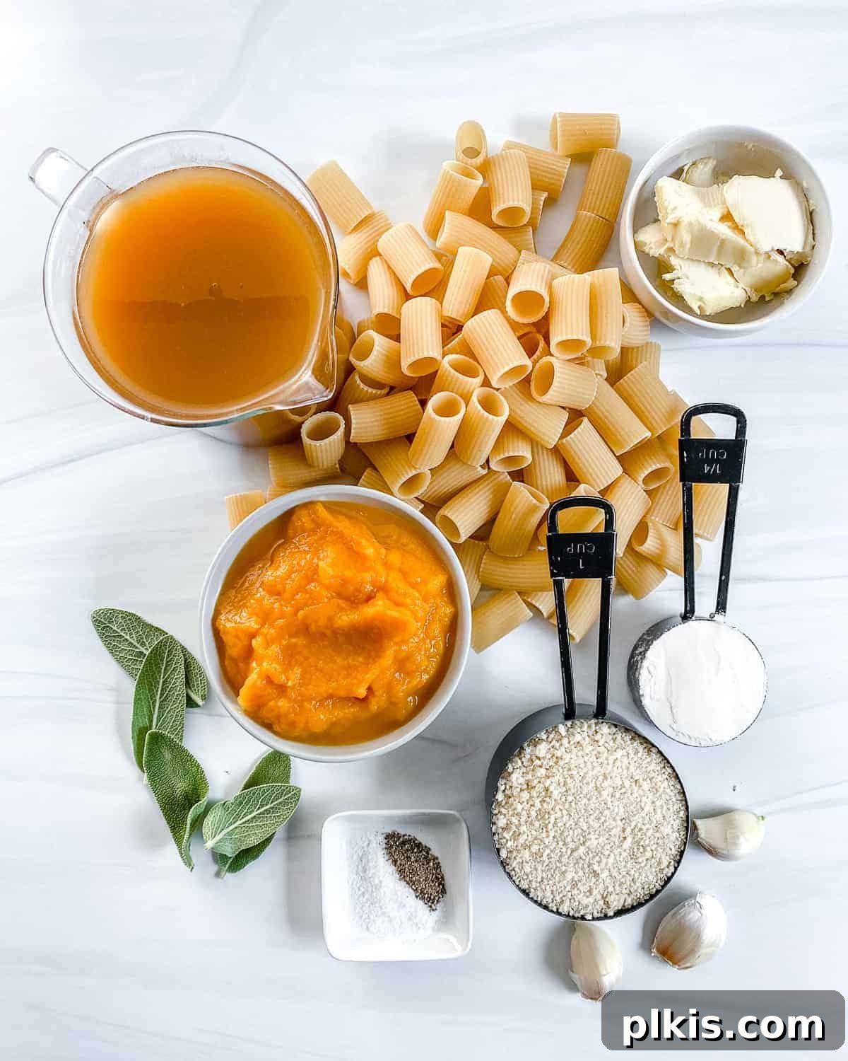 An array of fresh, wholesome ingredients laid out on a white surface, showcasing all the components needed for the vegan pumpkin pasta bake.