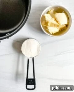 Close-up view of the initial ingredients being prepared in a black saucepan, including vegan butter, flour, garlic, and sage.