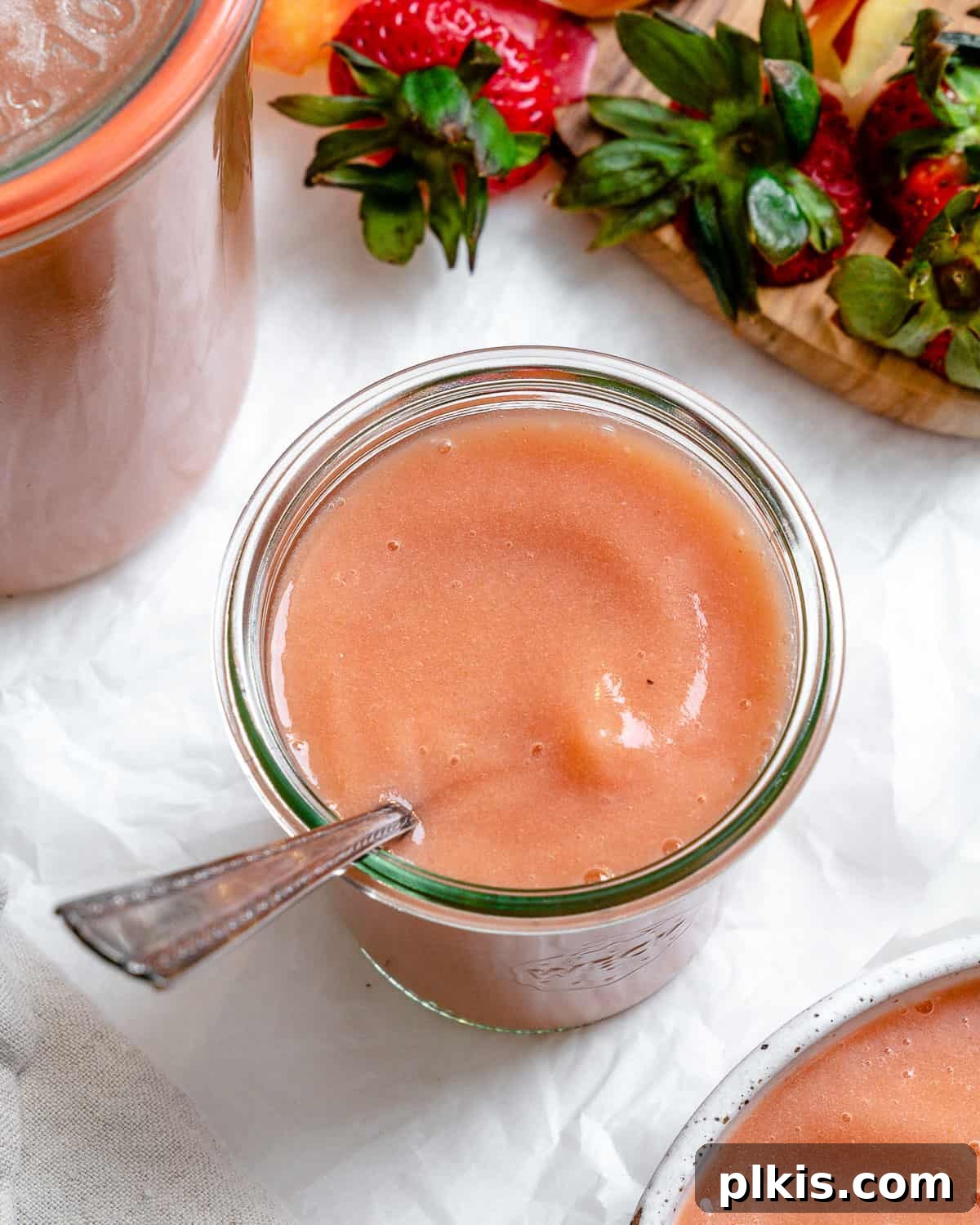 Blush Berry Apple Puree 2 completed Easy Strawberry Apple Sauce in a cup with a spoon against a white background