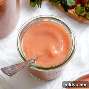 Blush Berry Apple Puree 11 completed Easy Strawberry Apple Sauce in a cup with a spoon against a white background