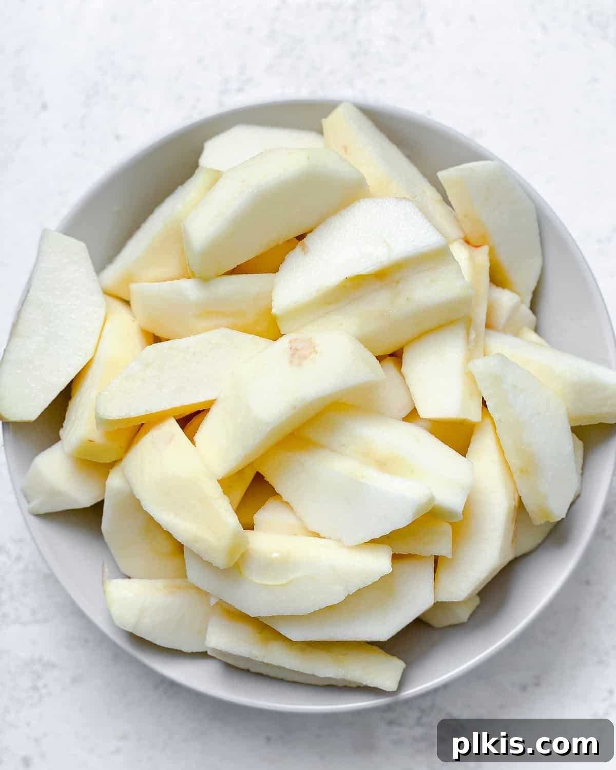 Blush Berry Apple Puree 4 sliced apples in a white bowl against a white background