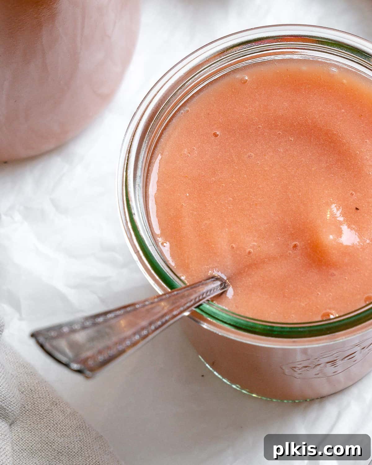 Blush Berry Apple Puree 10 completed Easy Strawberry Apple Sauce in a cup with a spoon against a white background