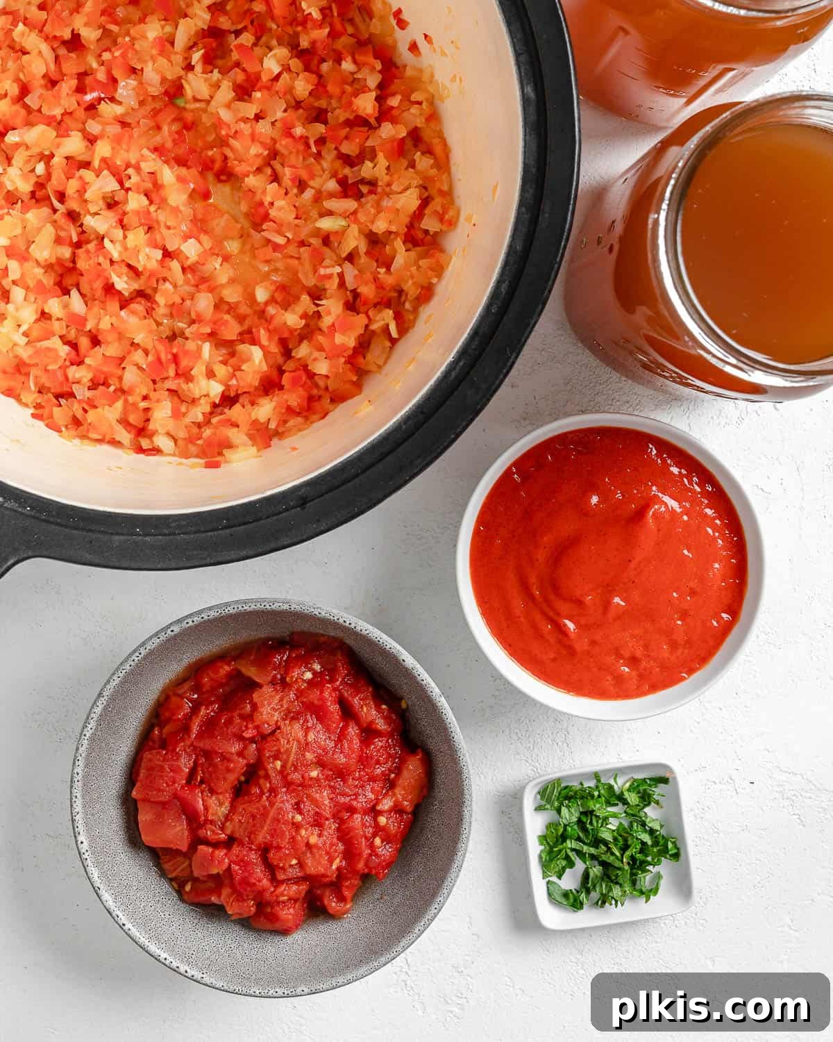 Turkish Embered Pepper Tomato Soup 11 A neat arrangement of measured ingredients for Turkish Tomato, Bulgur, and Red Pepper Soup on a white surface, including canned tomatoes, fresh mint, and pureed red peppers.