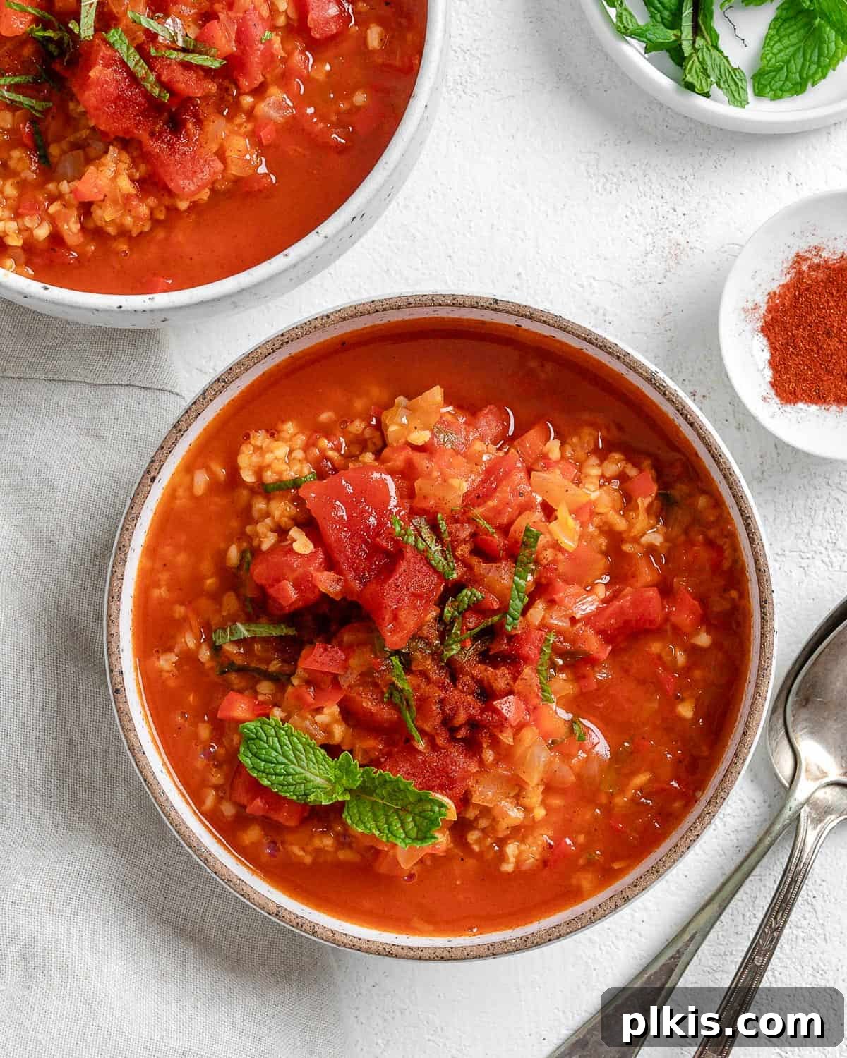 Turkish Embered Pepper Tomato Soup 16 Two inviting bowls of Turkish Tomato, Bulgur, and Red Pepper Soup, perfectly garnished, positioned side by side on a clean white surface, inviting a shared meal.
