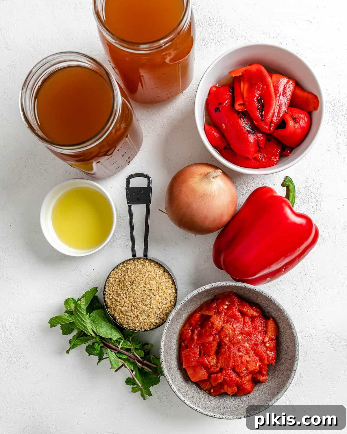 Turkish Embered Pepper Tomato Soup 3 A vibrant collection of fresh and canned ingredients for Turkish Tomato, Bulgur, and Red Pepper Soup arranged artfully against a clean white backdrop, showcasing the wholesome components.