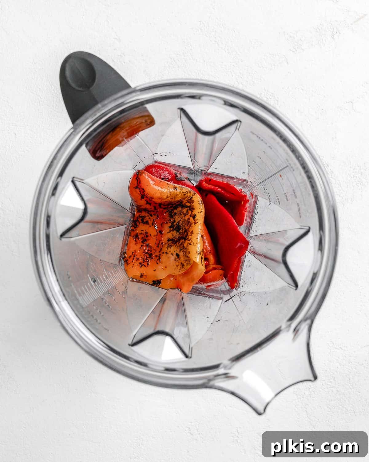 Turkish Embered Pepper Tomato Soup 5 Process shot of whole roasted red peppers being added to a blender for pureeing, a key step in creating the smooth base for Turkish Tomato, Bulgur, and Red Pepper Soup.