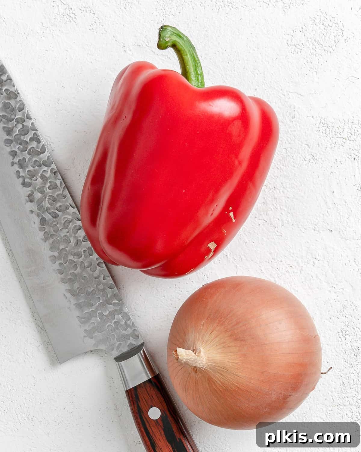 Turkish Embered Pepper Tomato Soup 7 A selection of fresh ingredients including minced onion and red bell pepper laid out on a white surface, prepared for cooking in the Turkish Tomato, Bulgur, and Red Pepper Soup.