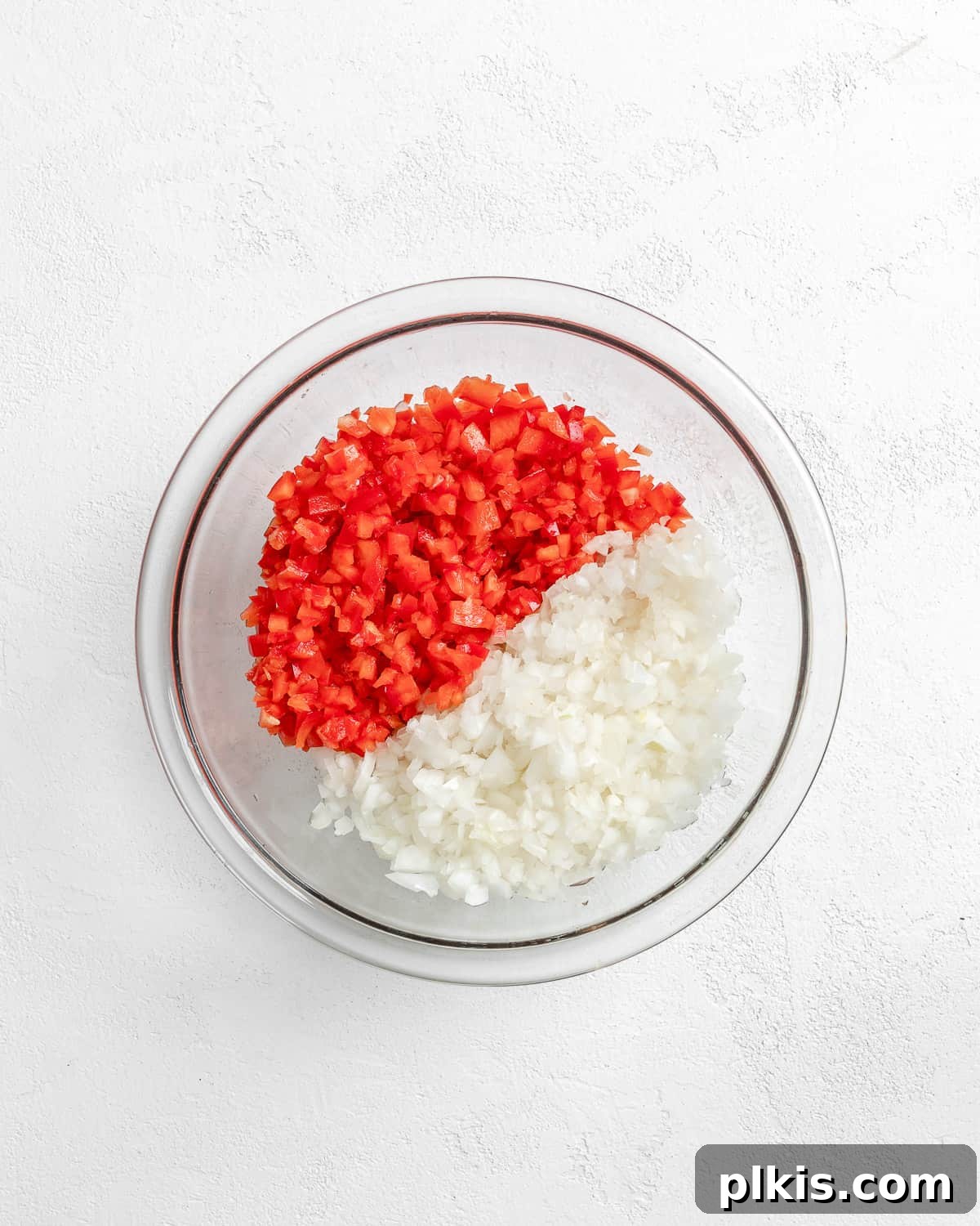 Turkish Embered Pepper Tomato Soup 8 A glass bowl holds finely minced red bell pepper and onion, indicating preparedness for the next stage of cooking the Turkish Tomato, Bulgur, and Red Pepper Soup.