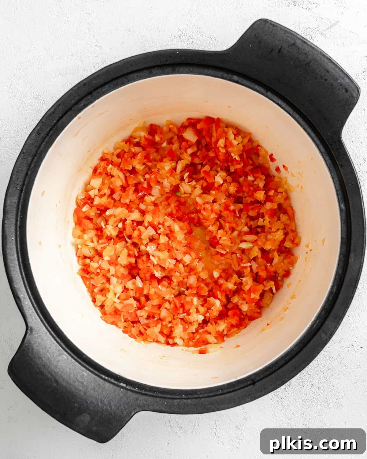 Turkish Embered Pepper Tomato Soup 10 Process shot of minced onion and red bell pepper gently cooking in a pan with oil, softening and releasing their aromas for the soup base.