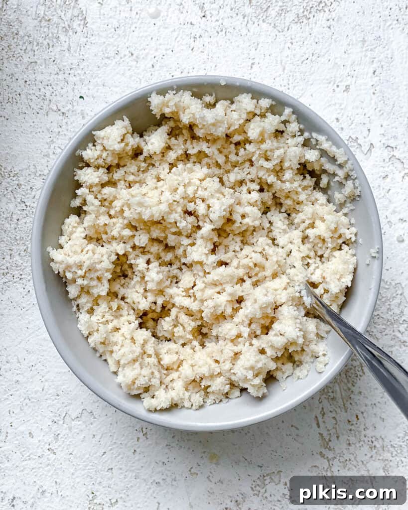 Process shot showing Panko breadcrumbs and plant-based milk being mixed together in a white bowl, initiating the stuffing preparation.